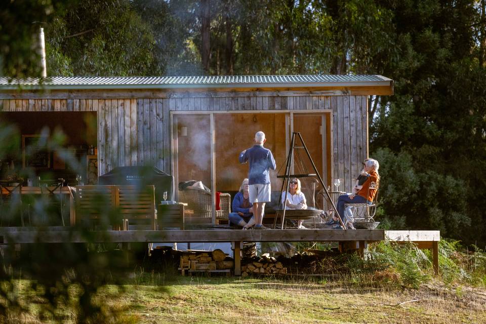 Guests sitting down around fire at Three Capes Lodge